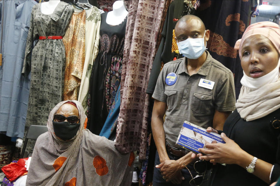 Fifth Congressional District candidate, Democrat Antone Melton-Meaux listens as Leila Shukri Adan, right, a consultant to Antone's campaign, interprets during an interview of a shopkeeper, left, at a mall that caters to the city's large Somali American community Wednesday, July 22, 2020. Melton-Meaux took his campaign to unseat Democrat Rep. Ilhan Omar to what should be a stronghold for her, giving Omar an unexpectedly strong, well-funded primary challenge in one of the country's most heavily Democratic congressional districts, which includes Minneapolis and some suburbs. (AP Photo/Jim Mone)