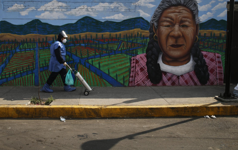 City worker Alexis Hernandez delivers a tank of oxygen to a COVID-19 patient, in the Iztapalapa borough of Mexico City, Friday, Jan. 15, 2021. The city offers free oxygen refills for COVID-19 patients. (AP Photo/Marco Ugarte)