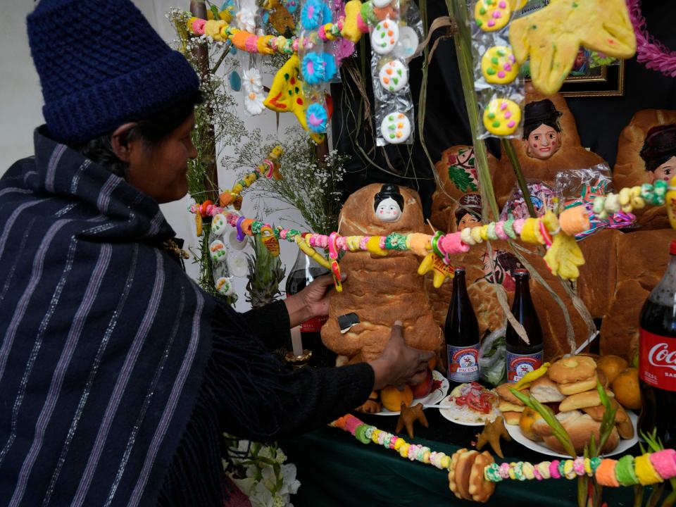 A relative prepares a table with offerings of food and flowers for his dearly departed during Day of the Dead celebrations in El Alto, Bolivia, Monday, Nov. 1, 2021.