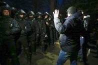 Protesters, who planned to stop buses carrying passengers evacuated from the Chinese city of Wuhan, speak to Ukrainian riot police blocking the road outside Novi Sarzhany, Ukraine, Thursday, Feb. 20, 2020. Several hundred residents in Ukraine's Poltava region protested to stop officials from quarantining the evacuees in their village because they feared becoming infected. Demonstrators put up road blocks and burned tires, while Ukrainian media reported that there were clashes with police, and more than 10 people were detained. (AP Photo/Efrem Lukatsky)