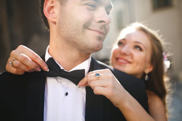 Woman tying a bowtie on a man in a tuxedo