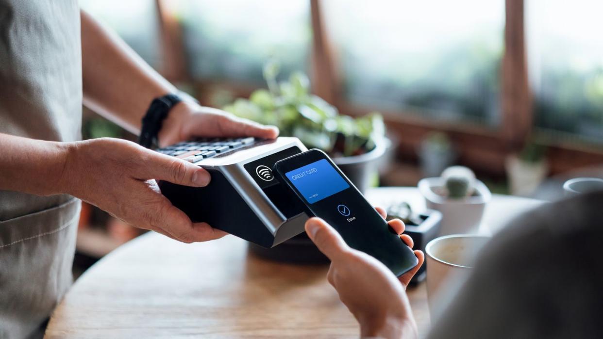 person paying bill with credit card contactless payment in cafe