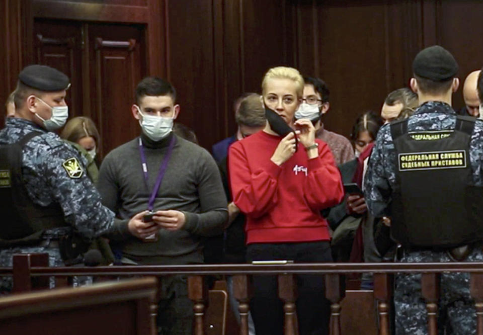 In this handout photo taken from a footage provided by Moscow City Court, the wife of Russian opposition leader Alexei Navalny, Yulia, in red, reacts attending a hearing to a motion from the Russian prison service to convert the suspended sentence of Navalny from the 2014 criminal conviction into a real prison term, in the Moscow City Court in Moscow, Russia, Tuesday, Feb. 2, 2021. A Moscow court has ordered Russian opposition leader Alexei Navalny to prison for more than 2 1/2 years for violating the terms of his probation while he was recuperating in Germany from nerve-agent poisoning. Navalny, who is the most prominent critic of President Vladimir Putin, had earlier denounced the proceedings as a vain attempt by the Kremlin to scare millions of Russians into submission. (Moscow City Court via AP)