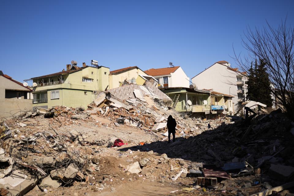 A man walks past debris from destroyed buildings in Golbasi, Turkey, Monday, Feb. 13, 2023. Thousands left homeless by a massive earthquake that struck Turkey and Syria a week ago packed into crowded tents or lined up in the streets for hot meals Monday, while the desperate search for anyone still alive likely entered its last hours. (AP Photo/Francisco Seco)