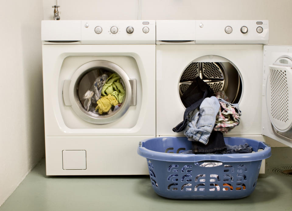 A basket of laundry in front of a washer and dryer