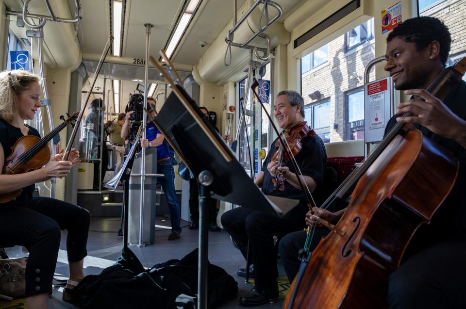 Rachel Harding Klaus, left, Mike Chen, center, and Cole Randolph, members of the Detroit Symphony Orchestra, perform inside a QLINE streetcar in Detroit on Aug. 17, 2022.