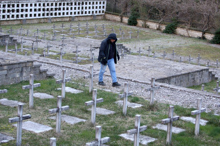 A man is seen walking at the Saint Nikolla church cemetery where fallen Greek World War Two soldiers are buried, in Kelcyra, Albania January 24, 2018. Picture taken January 24, 2018. REUTERS/Florion Goga