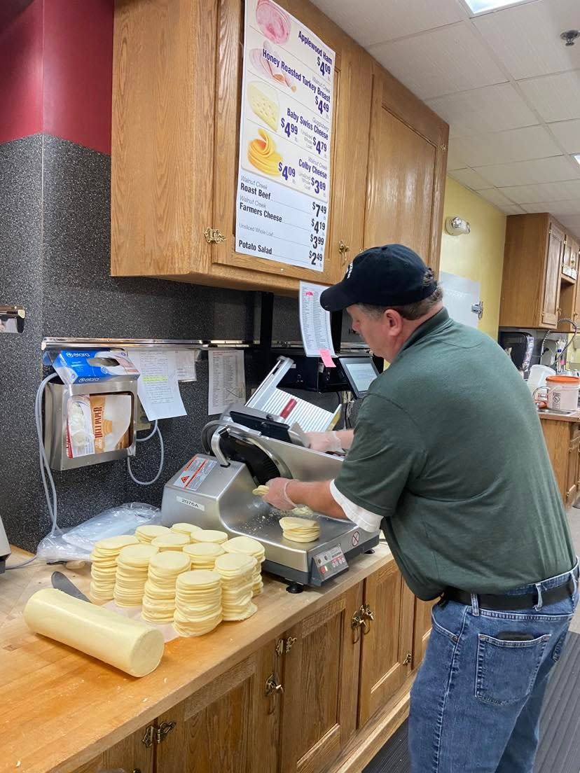 Richard Matheny slices cheese in the deli at the Walnut Creek Cheese location in Walnut Creek. Store manager Nick Blandin said deli items, water and ice are big sellers since Monday night's severe storms left many without power for days.