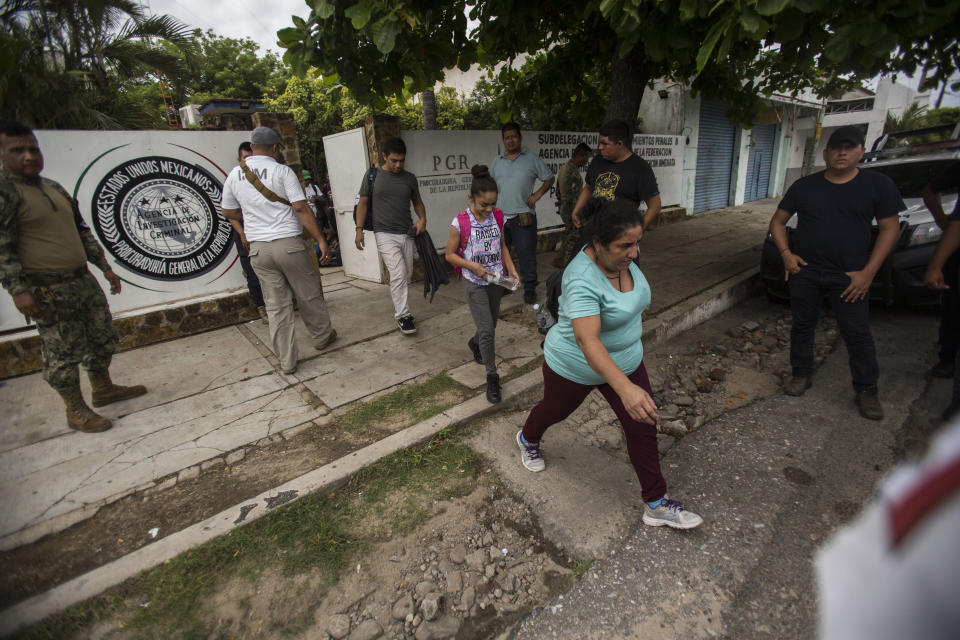 People without legal permission to be in Mexico leave an office of the Attorney General before being sent to Tapachula in an immigration van, as a member of the National Guard, left, stands watch in Arriaga, Mexico, Sunday, June 23, 2019. Mexico has completed its deployment of 6,000 National Guard agents to help control the flow of migrants headed toward the U.S. and filled immigration agency posts to regulate border crossings, the government said Friday. (AP Photo/Oliver de Ros)