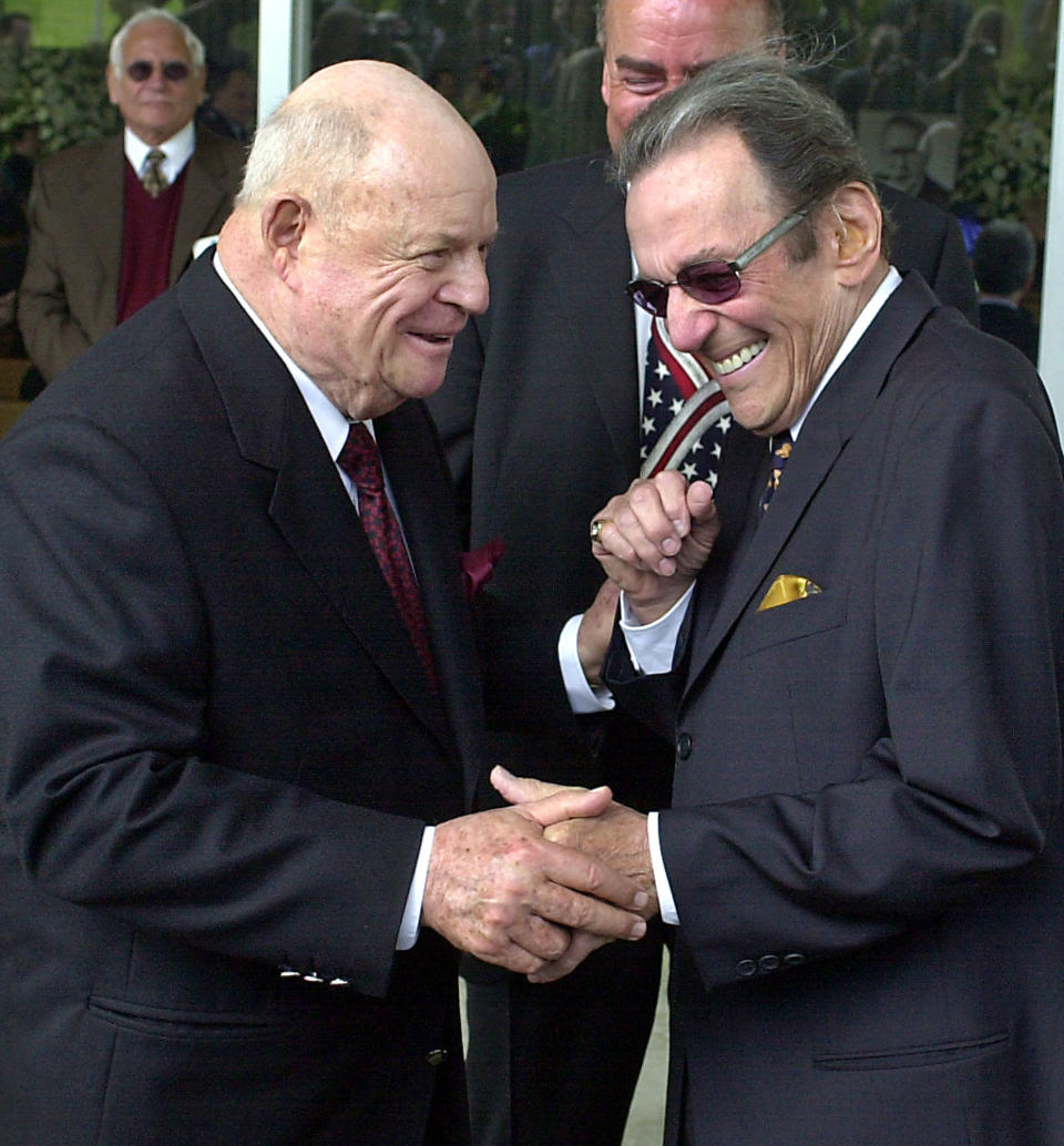 FILE - In this April 1, 2002, file photo, comedians Don Rickles, left, and Norm Crosby arrive for a ceremony honoring comedian Milton Berle at Hillside Memorial Park and Mortuary in Los Angeles. Crosby, the deadpan mangler of the English language who thrived in the 1960s, ’70s and ’80s as a television, nightclub and casino comedian, has died. He was 93. Crosby’s daughter-in-law, Maggie Crosby, told the New York Times that the comic died Saturday, Nov. 7, 2020 of heart failure in Los Angeles. (AP Photo/Nick Ut, File)