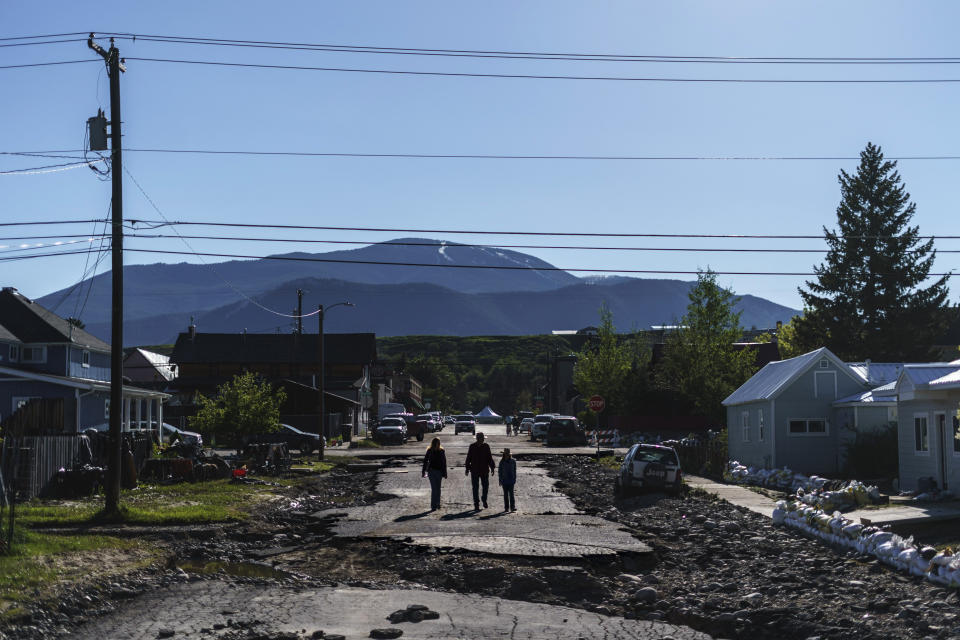 Pedestrians walk down a street washed away from Rock Creek floodwaters in Red Lodge, Mont., Wednesday, June 15, 2022. (AP Photo/David Goldman)