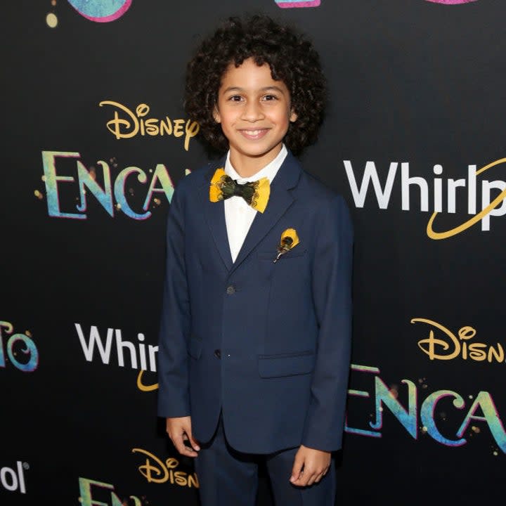 Ravi looking adorable at the film premiere in a suit, bowtie, and tennis shoes painted with scenes from Encanto