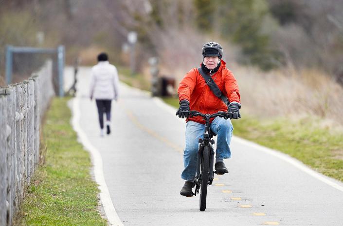 A cyclist rides an e-bike on the East Bay Bike Path in East Providence on Friday.