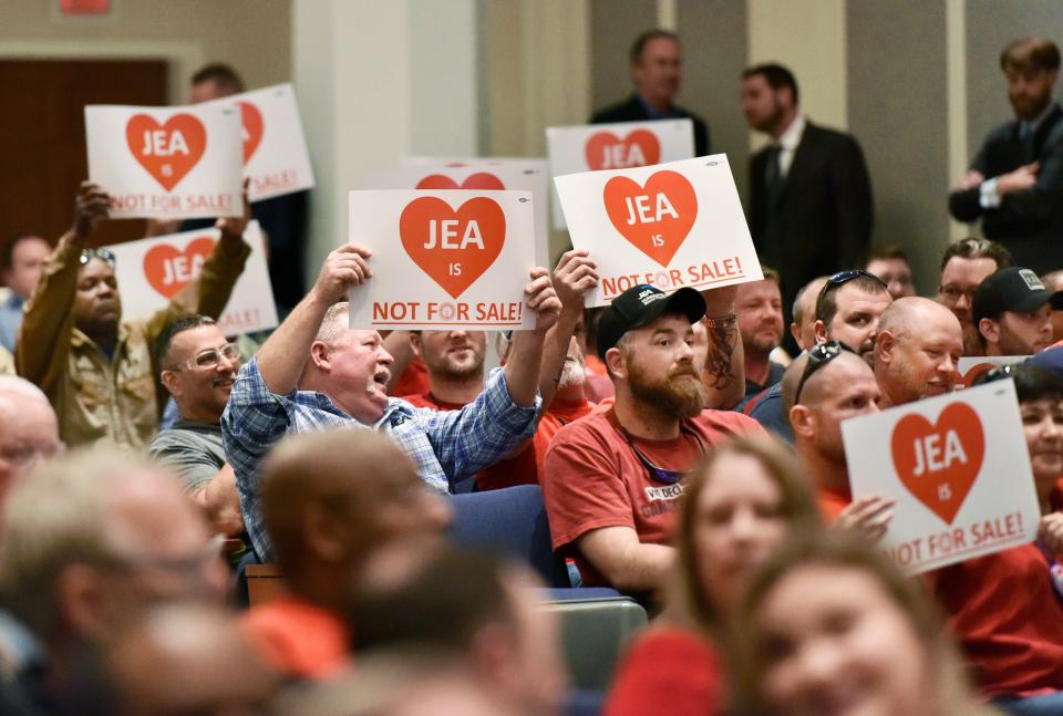 Audience members hold signs that read "JEA Not for Sale" during a special City Council meeting in February 2018.