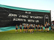 Port Adelaide players prepare to run through the banner paying tribute to their fallen teammate John McCarthy.