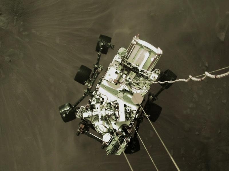 A view of the Perseverance rover taken from above by a camera on its rocket-powered descent stage as the six-wheel robot was lowered to the surface of Jezero Crater. The rover was about six feet off the ground when this photo was taken. / Credit: NASA/JPL-Caltech