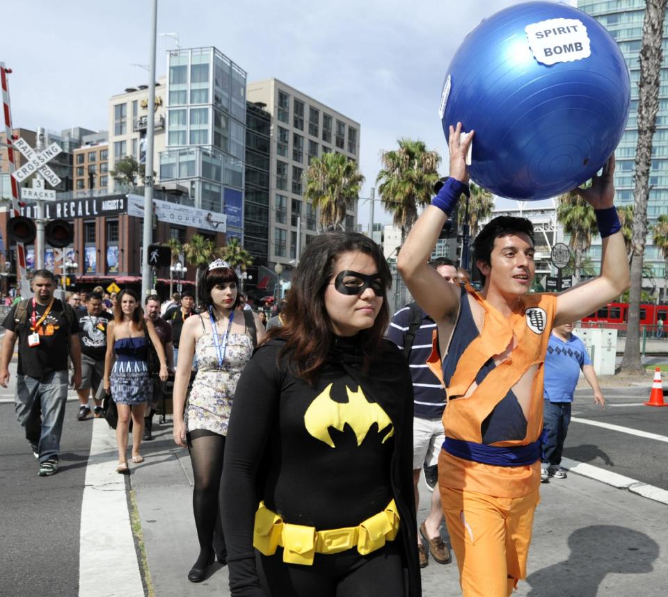 In this July 11, 2012 file photo, fans arrive in costume before preview night at the San Diego Convention Center as thousands of die-hard comic book fans gather for the annual Comic-Con International Convention, in San Diego. Superheroes dominate not only movie theaters but much of the pop culture landscape, from toys to clothes. (Photo by Denis Poroy/Invision/AP, File)