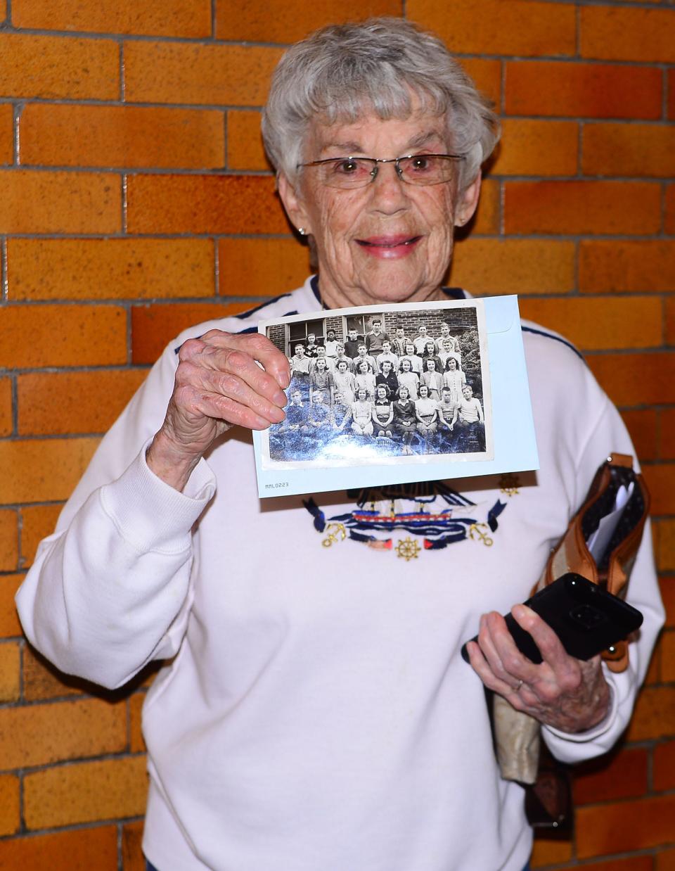 Marilyn Marty holds up a photo of her eighth-grade graduating class during an open house Tuesday, April 11, 2023, at North Lincoln School. Marty shared that she met her husband while attending the school from 1943-1946.