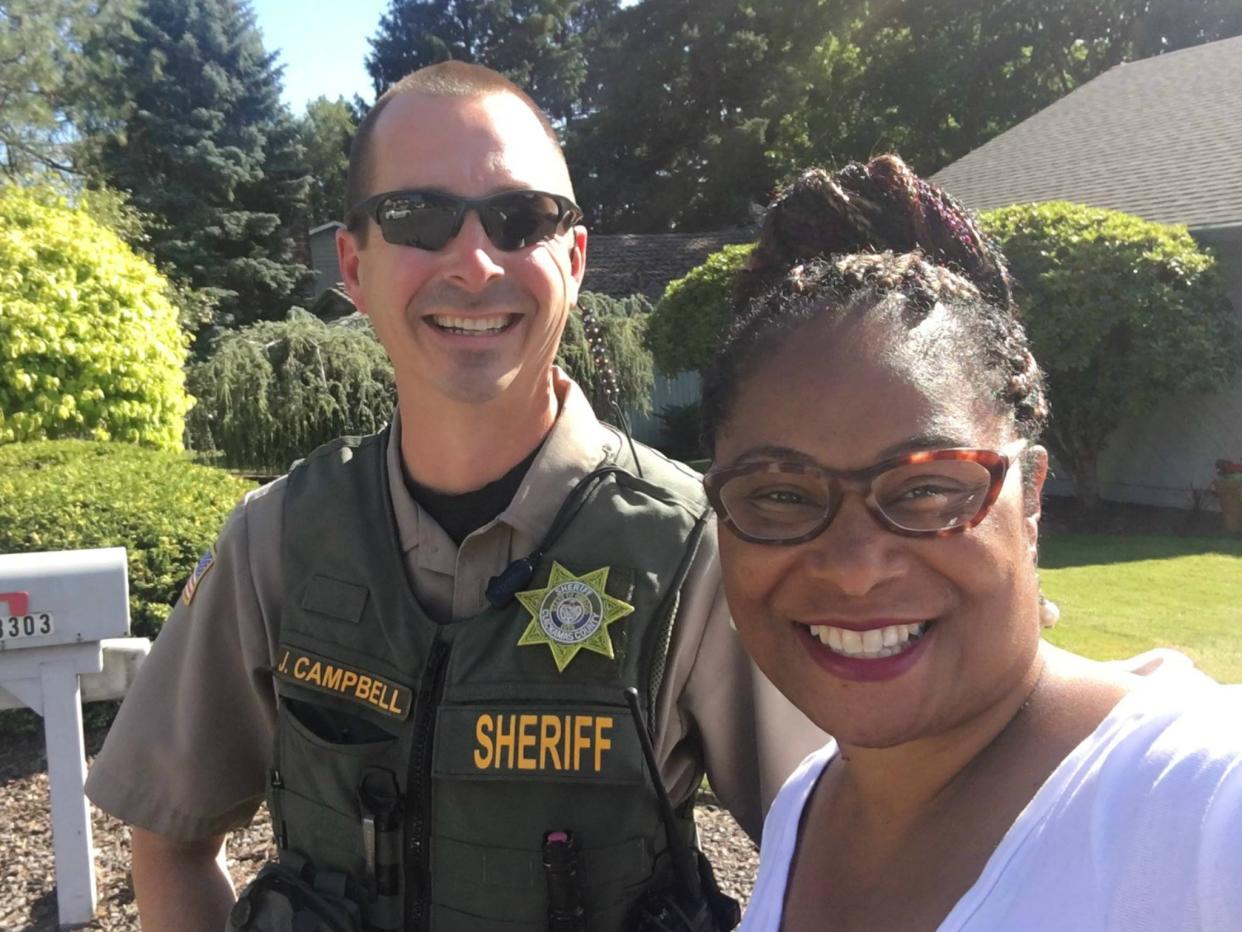 Oregon State Representative Janelle Bynum takes a picture with Officer Campbell of the Clackamas County Sheriff's office after a voter called police to report the candidate for campaigning door-to-door: Facebook/Janelle Bynum