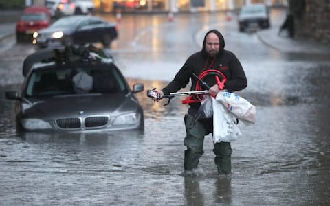 A man wades through a flooded street Sheffield - Credit: PA