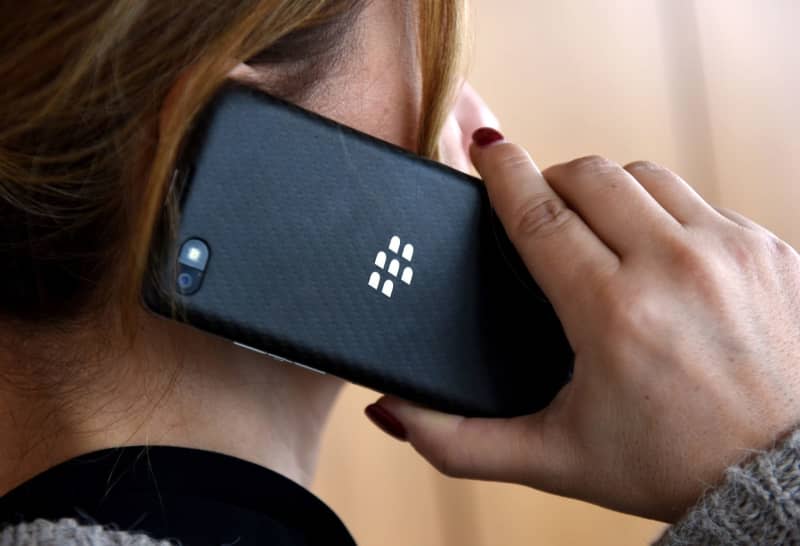 A woman talks on a Blackberry smartphone. Canada-based mobile phone technology company BlackBerry Ltd. said that it's aiming for $100 million of annualized net profit improvements, through a combination of cost reductions and margin expansion. picture alliance / dpa
