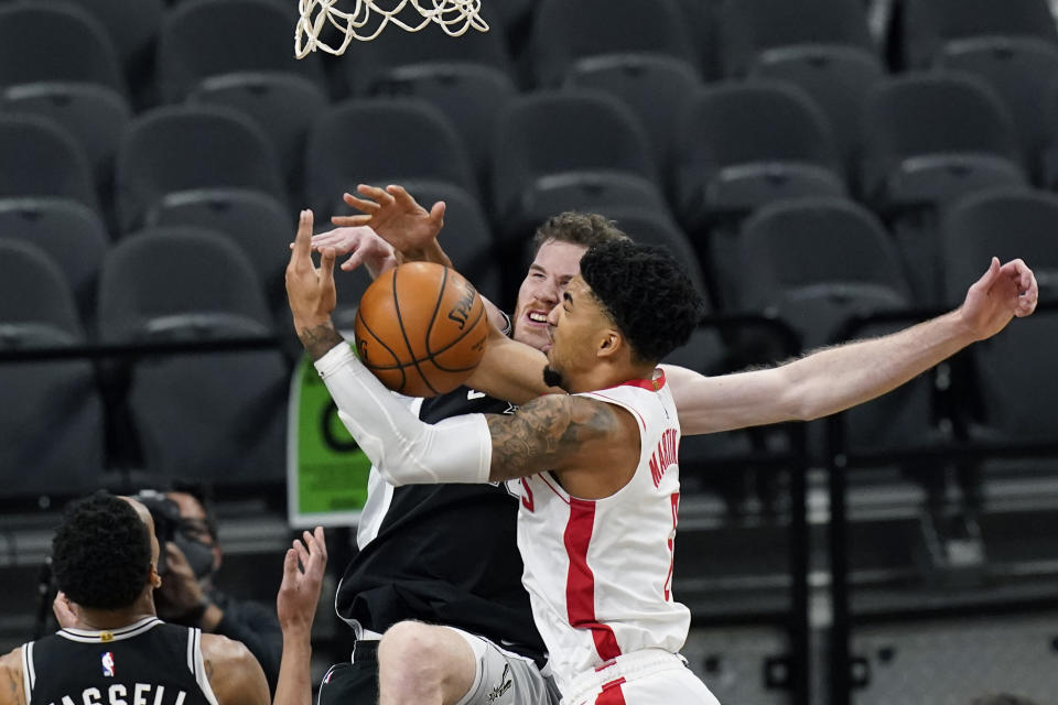 San Antonio Spurs center Jakob Poeltl, center left, and Houston Rockets forward Kenyon Martin Jr., right, scramble for a rebound during the first half of an NBA basketball game in San Antonio, Thursday, Jan. 14, 2021. (AP Photo/Eric Gay)