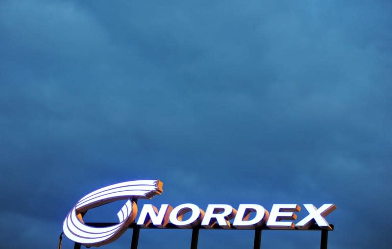 The lettering Nordex stands out against dark clouds on the roof of the rotor blade factory of the company Nordex in Rostock. Daniel Reinhardt/dpa