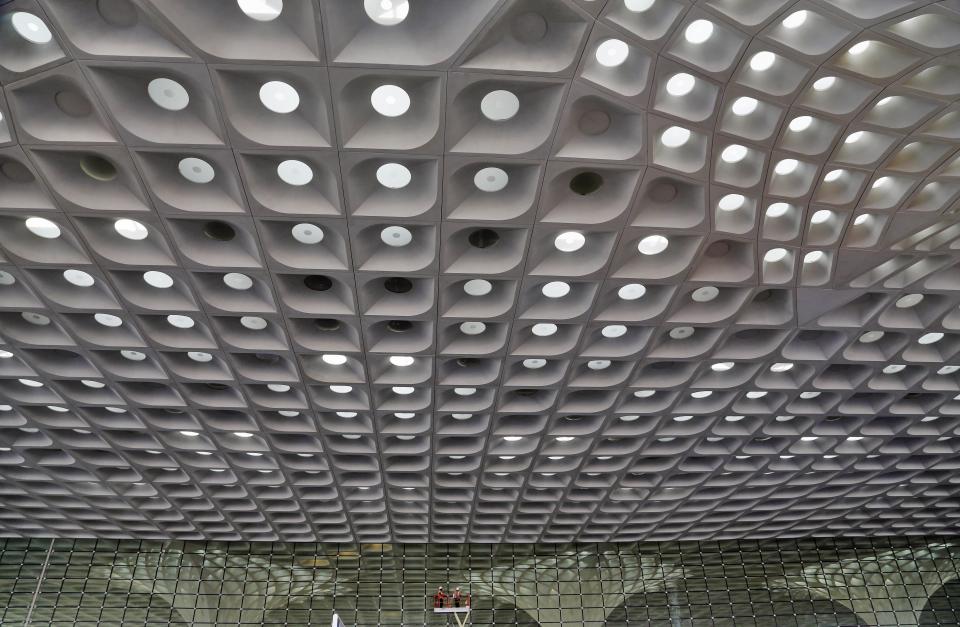 In this Wednesday, Jan. 8, 2014 photo, Indian workers put final touches on glass walls at the new airport terminal at the Chhatrapati Shivaji International Airport in Mumbai, India. India's overcrowded financial capital unveils its long-awaited $2 billion new airport terminal Friday, an ambitious, art-filled space that developers hope will be a showcase success in a country struggling to modernize inadequate infrastructure that is holding back economic growth. (AP Photo/Rajanish Kakade)