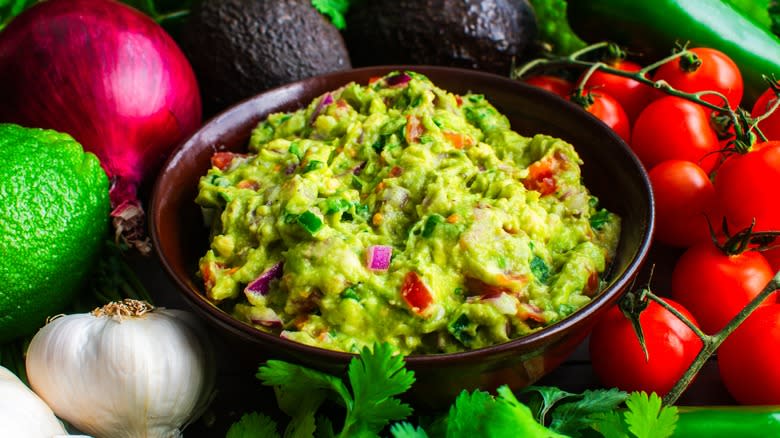 Bowl of guacamole surrounded by ingredients