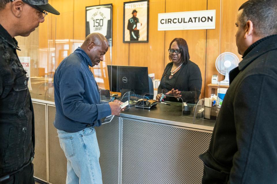 Ronnie Waters, 60, of West Bloomfield, left, looks on with Jose Burgos, 48, of Ecorse, at right, as Albert Garrett, 60, center, who was recently released from prison after 44 years, applies for his library card at the Detroit Public library with the help of Yvette Williams, a senior customer service representative at the library, on Monday, May 1, 2023. Both Burgos and Waters are part of an advocacy effort to end the practice of sentencing juveniles to life in prison without parole in Michigan.