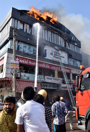 Firefighters douse a fire that broke out in a four-story commercial building in Surat, in the western state of Gujarat, India, May 24, 2019. REUTERS/Stringer