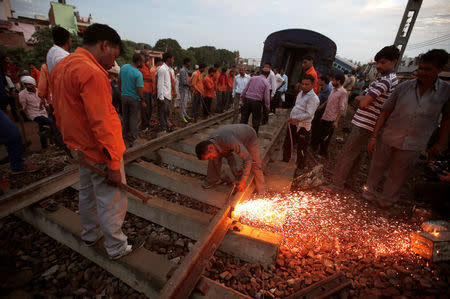 A railway worker repairs the tracks next to derailed coaches of a passenger train, at the site of an accident in Khatauli, in the northern state of Uttar Pradesh, India August 20, 2017. REUTERS/Adnan Abidi TPX IMAGES OF THE DAY