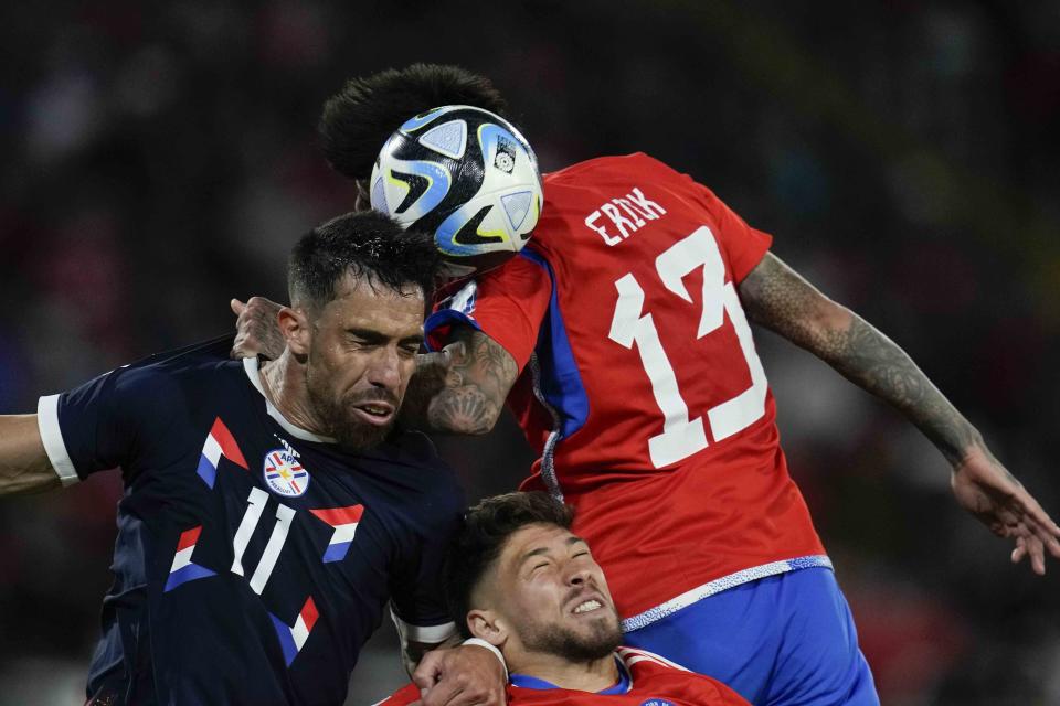 Gabriel Ávalos, de Paraguay, y Erick Pulgar, de Chile, disputan un centro en el partido de la eliminatoria mundialista disputado el jueves 16 de noviembre de 2023 en Santiago (AP Foto/Esteban Félix)