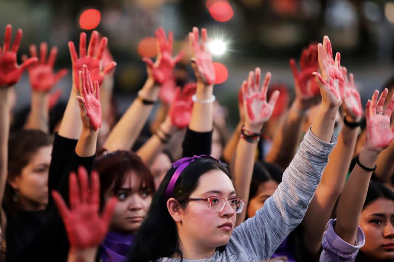 Mujeres levantan sus manos pintadas de rojo en una protesta en contra de la violencia de género y el feminicidio, en Puebla, México