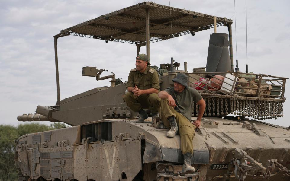 Israeli soldiers sit on a tank at an army staging area near Israel's border with Gaza, southern Israel, Saturday Nov. 25, 2023.