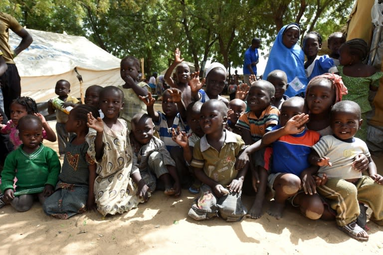 Children wave at the camera in a camp for Internally Displaced Persons in Maiduguri, northeast Nigeria, on February 4, 2016