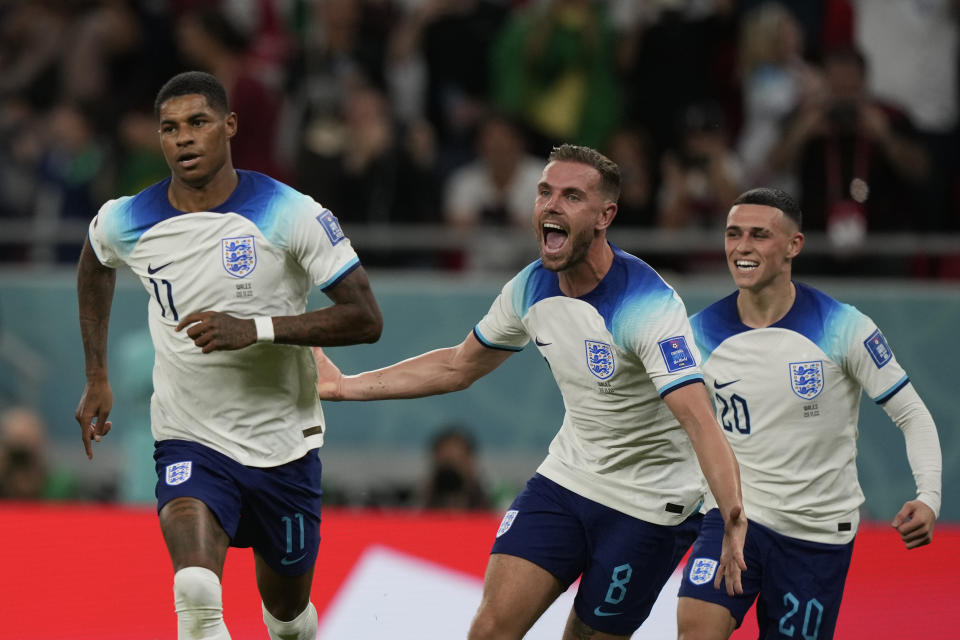 England's Marcus Rashford, left, celebrates with teammates after scoring the opening goal during the World Cup group B soccer match between England and Wales, at the Ahmad Bin Ali Stadium in Al Rayyan , Qatar, Tuesday, Nov. 29, 2022. England won 3-0. (AP Photo/Frank Augstein)