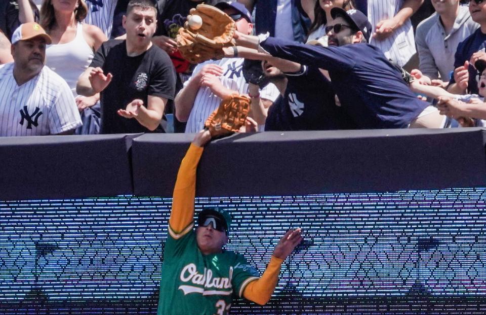 JJ Bleday's effort to make a play was impeded by two fans in the stands. (AP Photo/Bebeto Matthews)