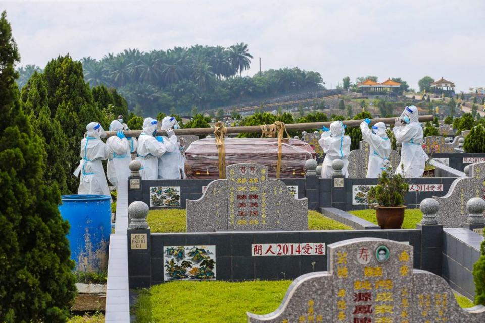 Workers wearing personal protective equipment carry a coffin containing the remains of a Covid-19 patient at a cemetery in Fairy Park, Klang August 1, 2021. — Picture by Yusof Mat Isa