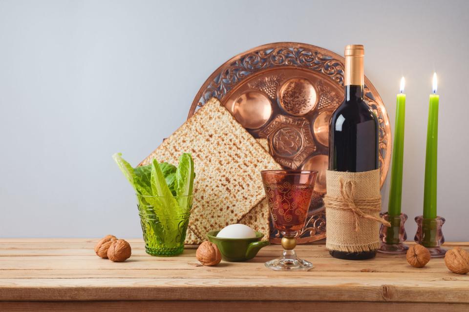 Jewish holiday Passover celebration concept with wine, matzah and seder plate on wooden table over gray background.