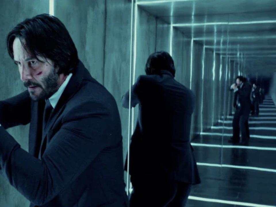 Keanu Reeves as John Wick in a mirrored room.
