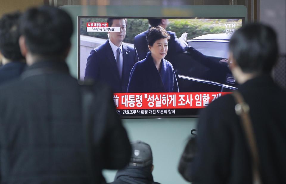People watch a TV news program showing South Korean ousted President Park Geun-hye's arrival at prosecutors office, at Seoul Railway Station in Seoul, South Korea, Tuesday, March 21, 2017. Park said Tuesday she was "sorry" to the people as she underwent questioning by prosecutors over a corruption scandal that led to her removal from office. The letters read "Park Geun-hye arrives at prosecutors office." (AP Photo/Ahn Young-joon)