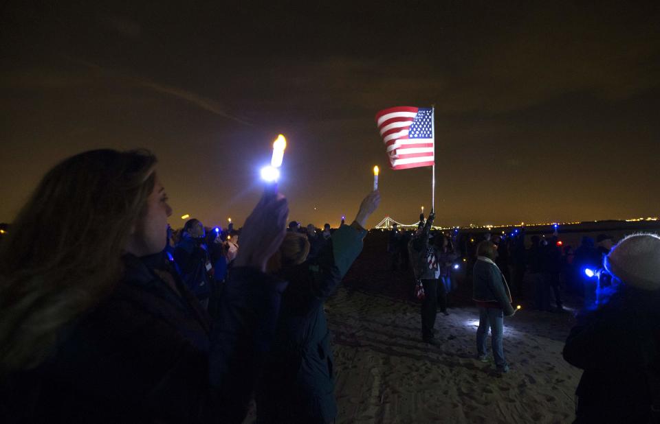 Staten Island residents in New York City hold lights and candles as they stand on Midland Beach during a an event to commemorate the one-year anniversary of Hurricane Sandy in New York