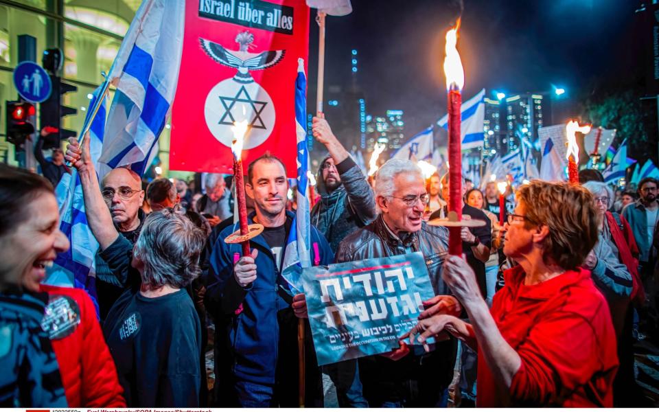 A protester holds a placard that says "Jewish and racist, right" during an anti Judicial reform night protest in Tel Aviv - Eyal Warshavsky/SOPA Images/Shutterstock