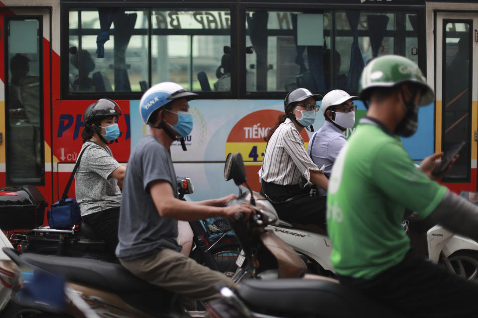 People wear face masks in hopes of curbing the spread of the coronavirus riding mopeds in Hanoi, Vietnam on Thursday, Aug. 6, 2020. Vietnamese health official said on Thursday the COVID-19 outbreak would peak in the coming ten days as the country reported another death and a score of new infections. (AP Photo/Hau Dinh)