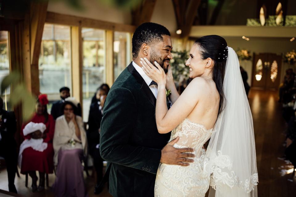 A bride and groom embrace and grin at each other during their wedding ceremony.