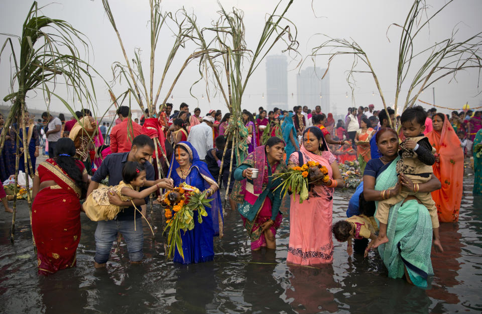 In this Tuesday, Nov. 13, 2018, file photo, Hindu devotees pray to the Sun god as they stand in knee-deep waters in River Yamuna, during the Chhath festival in New Delhi, India. (AP Photo/Altaf Qadri, File)