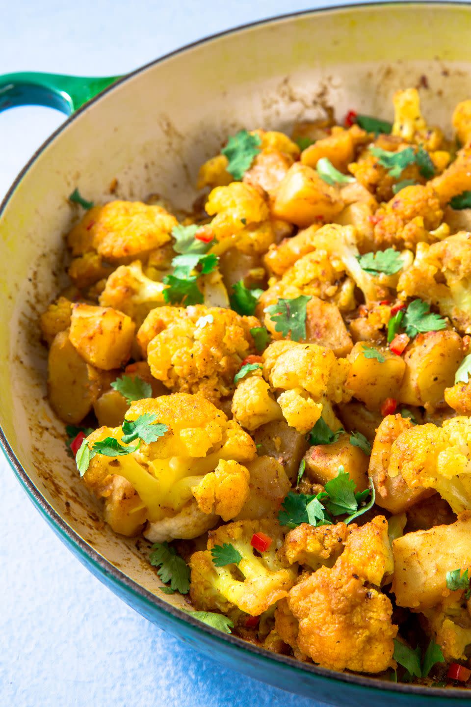 close up of yellow aloo gobi in a blue bowl