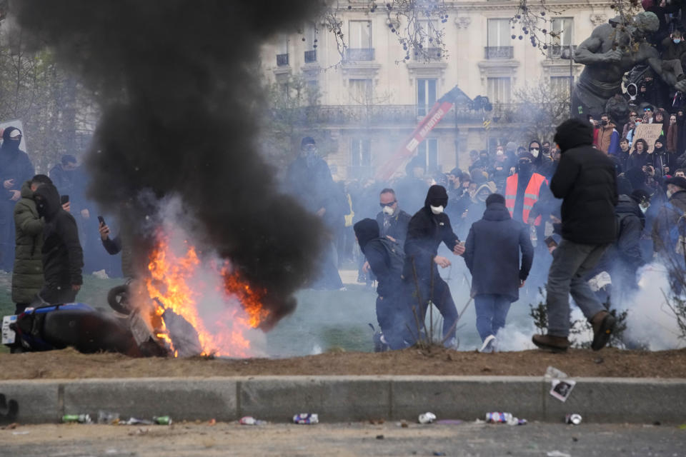 Youths gather near a burning scooter after a demonstration Tuesday, March 28, 2023 in Paris. It's the latest round of nationwide demonstrations and strikes against unpopular pension reforms and President Emmanuel Macron's push to raise France's legal retirement age from 62 to 64. (AP Photo/Christophe Ena)