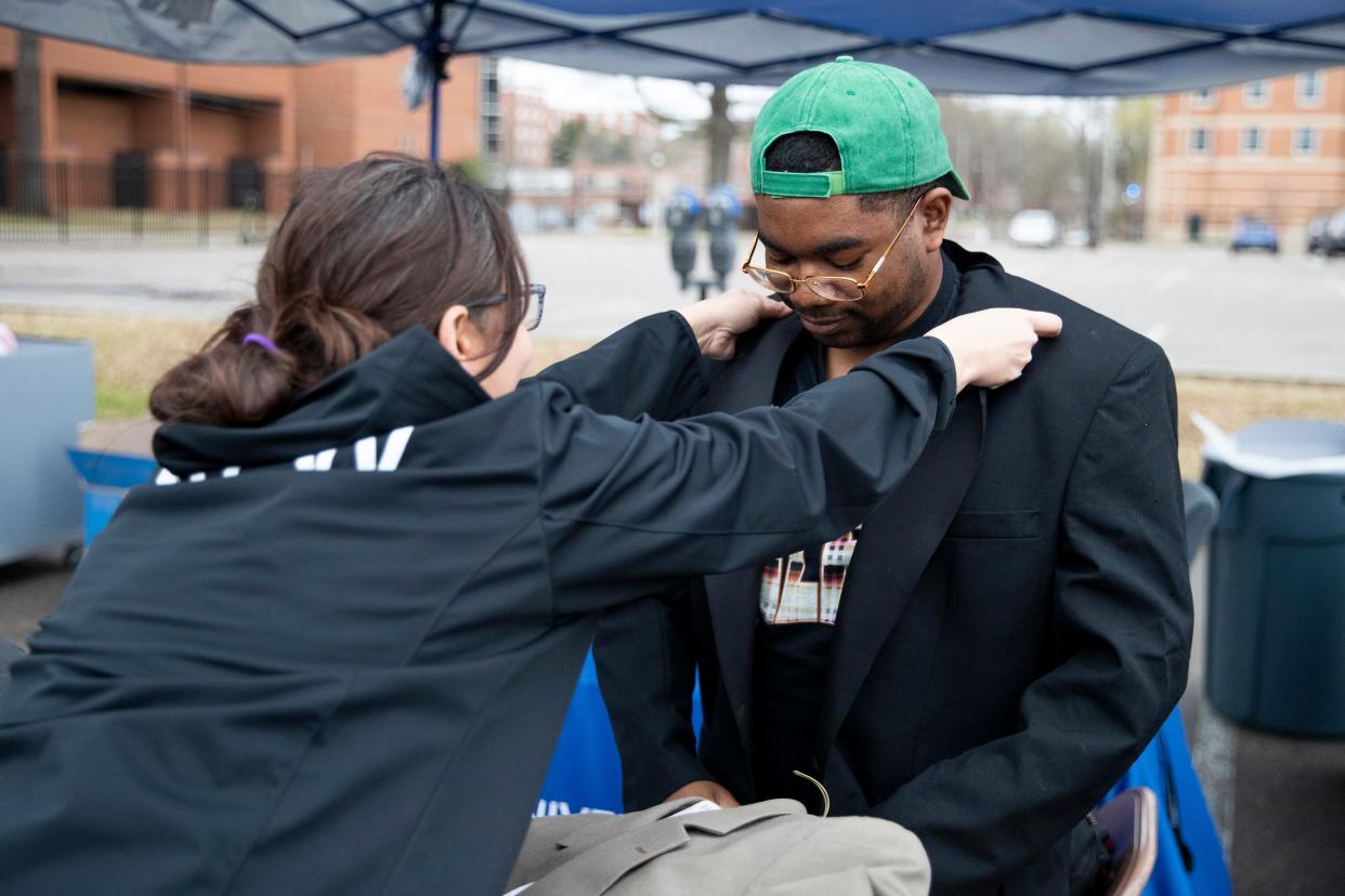 Jacki Rodriguez, director of the office of first-generation student success, straightens the collar of a suit jacket D’Angelo Johnson, a first-generation student, is trying on that had been donated for the career closet donation drive at the University of Memphis on Friday, March 8, 2024. The donation drive serves to give first-generation students access to professional clothing.